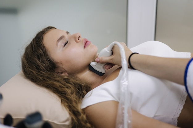 Woman receiving non-invasive radiofrequency treatment for chin and neck contouring in a modern clinic