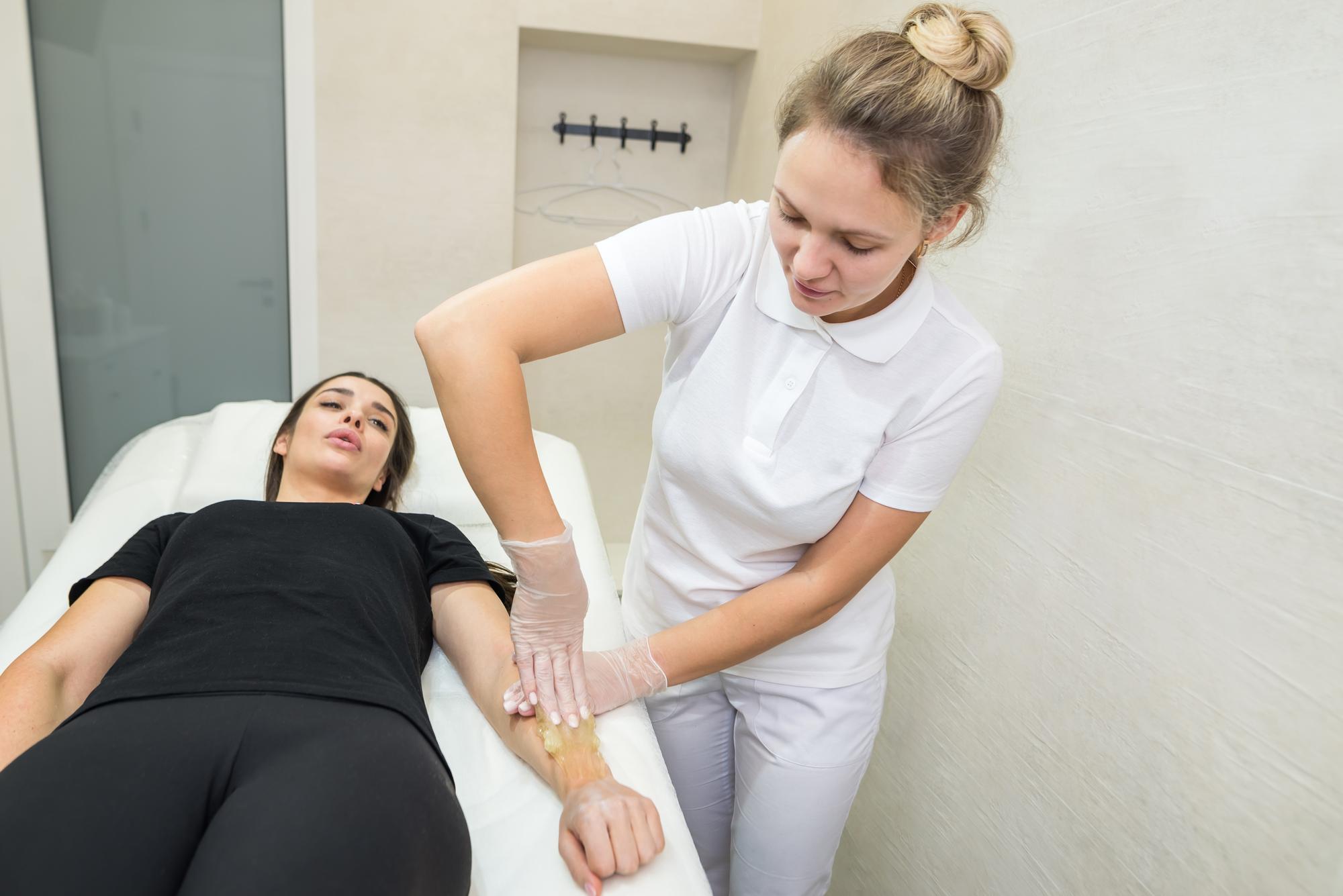 Woman showing her slim arms after arm liposuction in Tunisia, smiling in a modern clinic
